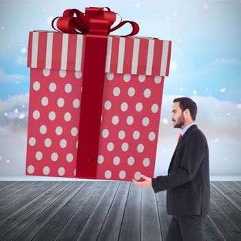 Stylish man with giant gift against clouds in a room