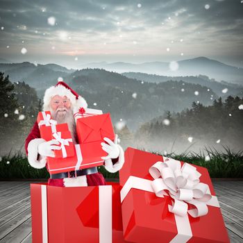 Santa standing in large gift against mountain range beyond wooden floor