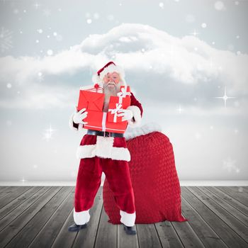 Santa holding pile of gifts against clouds in a room