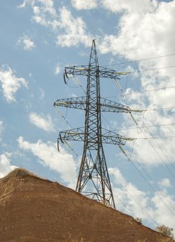 high voltage tower against the blue sky with clouds