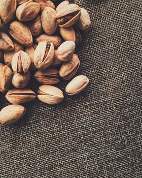 Pistachio nuts on rustic linen background, food and nutrition