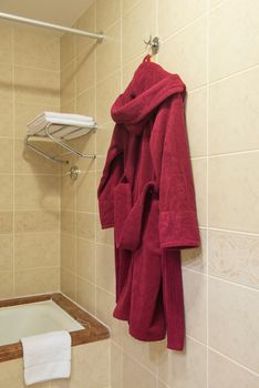 a red bathrobe hanging in the hotel bathroom