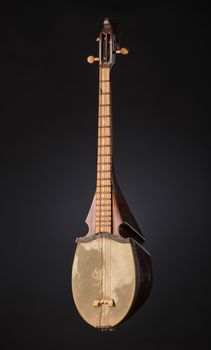 ancient Asian stringed musical instrument on black background with backlight