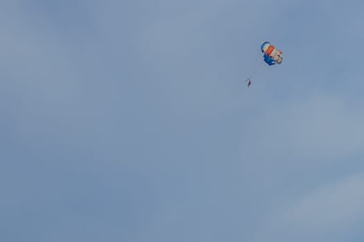 Parasailing. Man parachuting behind a boat against a blue sky