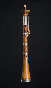 ancient asian woodwind musical instrument on a black background, surnay