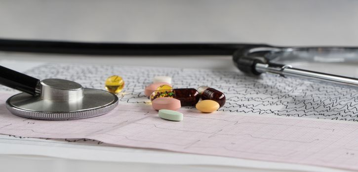 medical stethoscope with pills and cardiogram on a light background