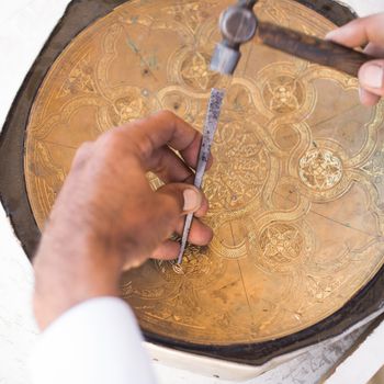 craftsman engraving patterns on the tray. masters of Central Asia. manual copper minting