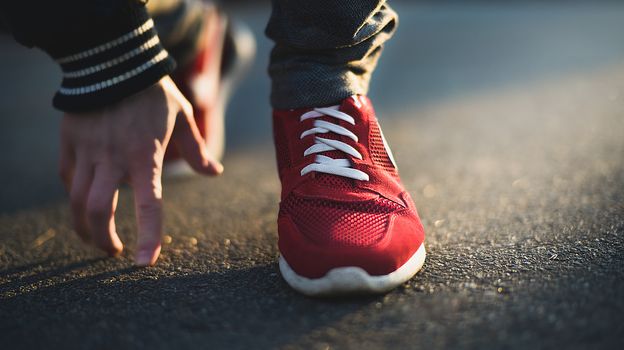 Unrecognizable man stopping lacing shoe outdoors. Athletic shoes concept. Jogging in the park