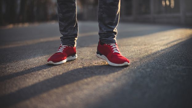 Man in red sport sneakers walks down the street on a sunny day