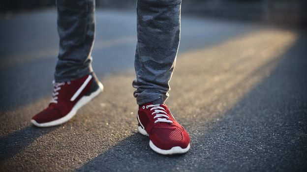 Man in sneakers walks down the street on a sunny day