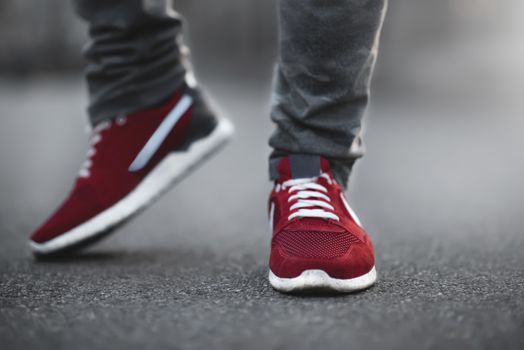 Sports red sneakers close-up on asphalt. Legs and shoes from the lower angle