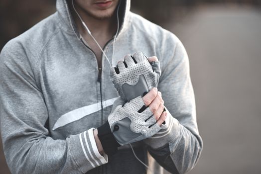 A Man on the street puts on his hands sports gloves and prepares for coaching.