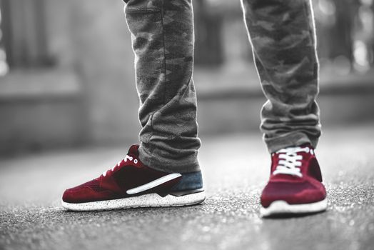 Sports red sneakers close-up on asphalt. Legs and shoes from the lower angle