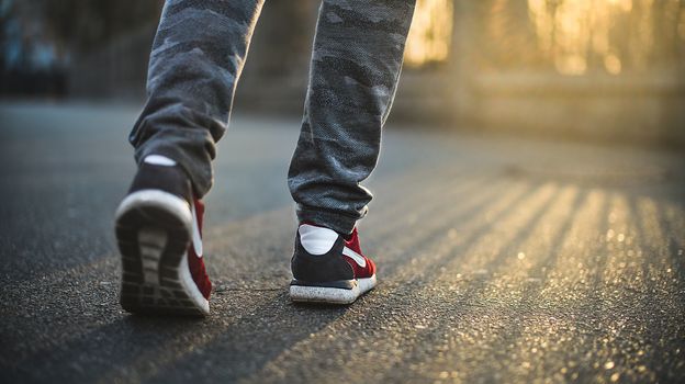 Man in red sport sneakers walks down the street on a sunny day