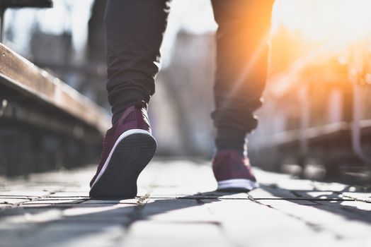 Man in sneakers walks down the street on a sunny day