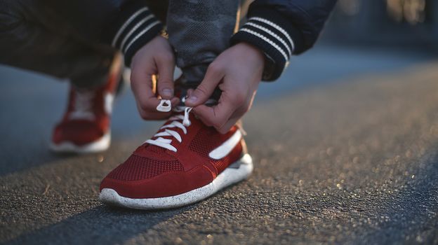 Hands of sportsman with pedometer tying shoelaces on sporty sneaker. Running equipment concept. Shoelaces tying by male hands.