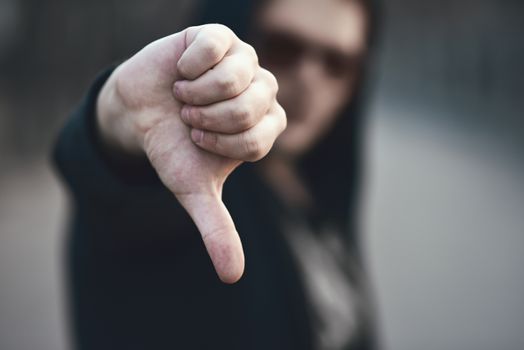 Portrait of fashion man in a black sweater with a hood and sunglasses, hand gestures.