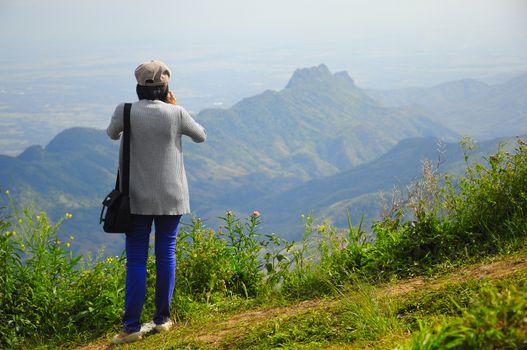 Rear view of woman standing on mountain against sky.