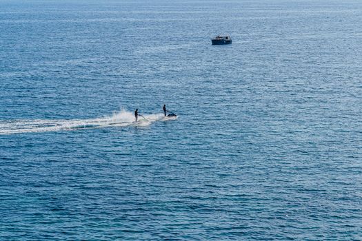 two people ride water bikes in the sea on the background of the boat, summer day