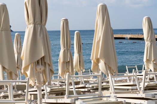 Folded beach umbrellas on the background of the sea. The beach is getting ready to open.