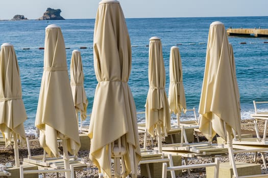 Folded beach umbrellas on the background of the sea. The beach is getting ready to open.