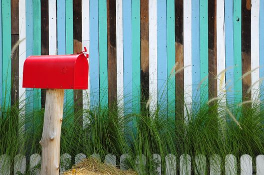 Red mailbox on a multicolored lath background.