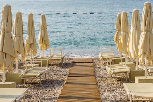 Folded beach umbrellas on the background of the sea. The beach is getting ready to open.