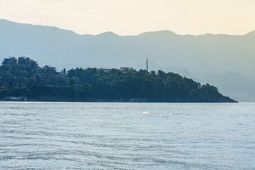 Seashore, a hill with buildings of hotels and resorts. View at sunset.