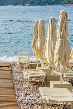 Folded beach umbrellas on the background of the sea. The beach is getting ready to open.