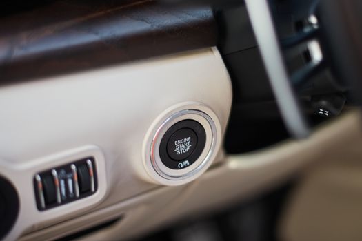 A Start-stop button to start the engine in a luxury car. A button located on the left side of the steering wheel.