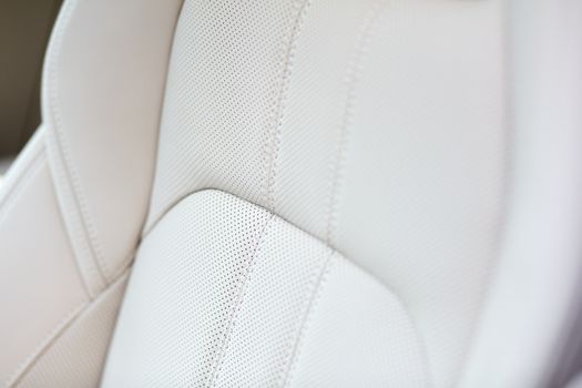 White leather seat of an expensive and luxurious car. Shallow depth of field.