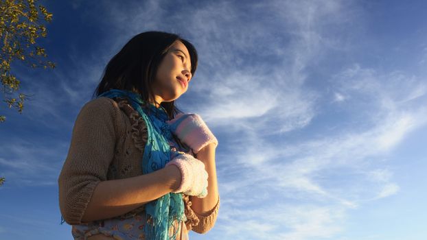 The girl stands in the first light of the day with a blue sky background, shooting in a low angle.