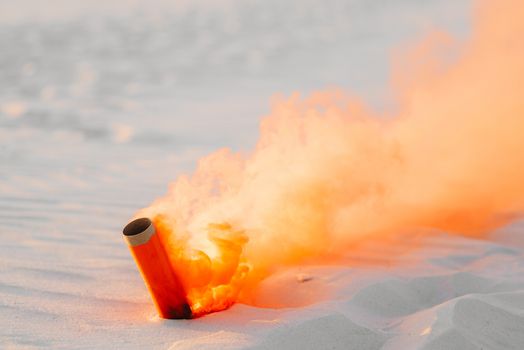 smoke bomb with orange smoke stuck in the white sand