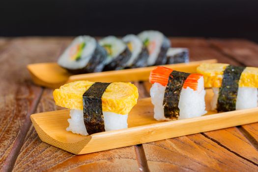 Tamagoyaki sushi or sweet egg on rice and seaweed wrap on wooden tray and table. Delicious japanese food.