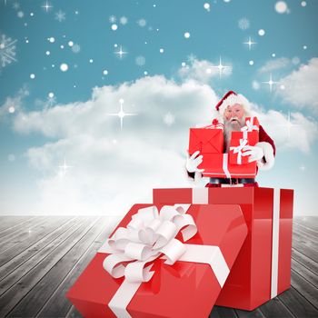 Santa standing in large gift against cloudy sky background