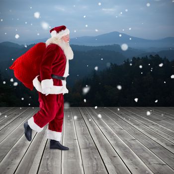 Santa carrying sack of gifts against wooden planks against mountains
