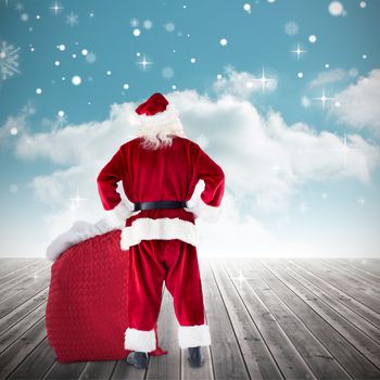 Santa with sack of gifts against cloudy sky background