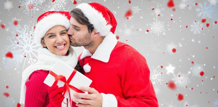 Festive young couple holding gift against snowflake pattern