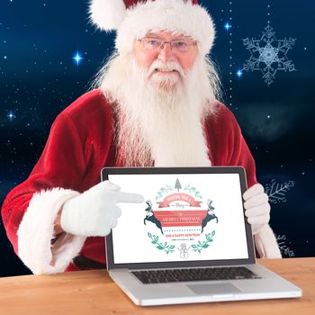 Happy Santa showing laptop screen against snowflakes hanging against starry sky