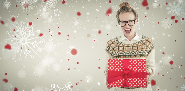 Excited geeky hipster holding present  against snowflake pattern