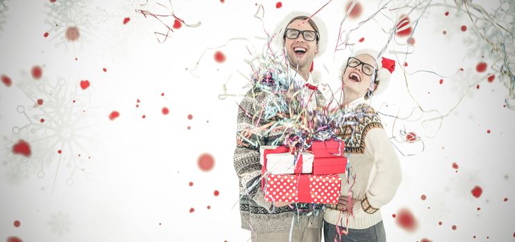 Happy man holding gifts and woman during Christmas  against snowflake pattern
