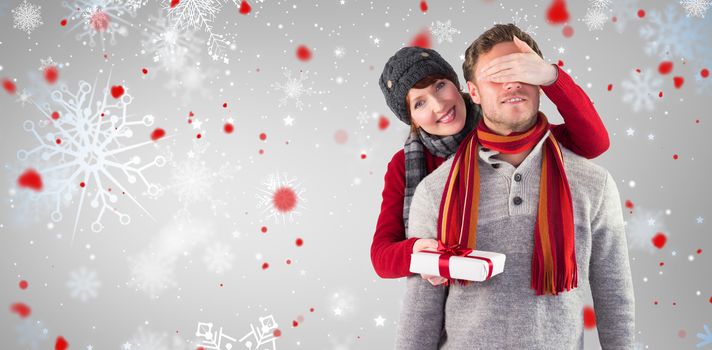 Woman giving man a present against snowflake pattern