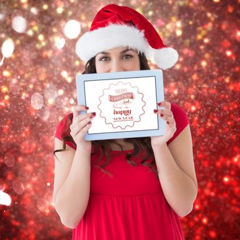 Festive brunette showing a tablet  against white snow and stars on red