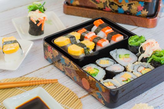 Set of variety sushi, Tamagoyaki, crabsticks sushi and maki in bento box served with soy sauce and wasabi. Delicious japanese food.