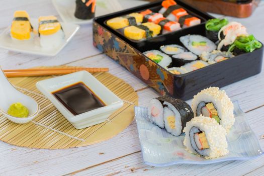 Set of variety sushi, Tamagoyaki, crabsticks sushi and maki in bento box served with soy sauce and wasabi. Delicious japanese food.