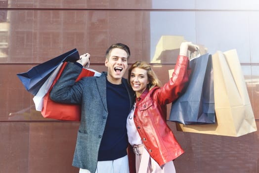 Beautiful young loving couple carrying shopping bags and enjoying together. Picture showing young couple shopping in the city.