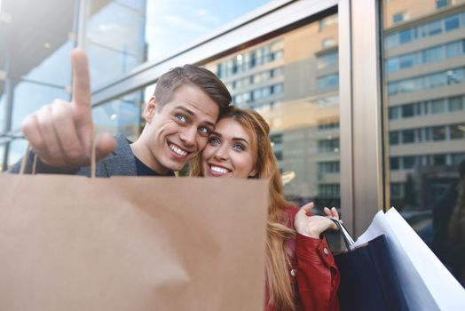 Beautiful couple with shopping bags is talking and smiling while doing shopping in the mall focus on the woman. hot discounts