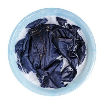 Blue jeans with liquid detergent in the plastic basin isolated on white background