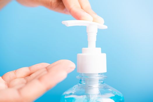 Close up Asian young woman applying press dispenser sanitizer alcohol gel pump to hand wash cleaning, hygiene prevention COVID-19 or coronavirus protection concept, isolated on blue background