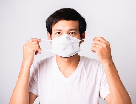 Closeup Asian handsome Man wearing surgical hygienic protective cloth face mask against coronavirus, studio shot isolated white background, COVID-19 medical concept